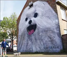  ?? ZHENG HUANSONG / XINHUA ?? A man passes by a wall painting on a building in Ostend, Belgium, on May 18. The coastal city has attracted many artists from around the world to join in wall painting and graffiti in recent years.