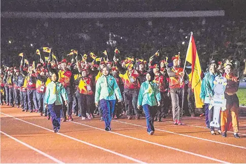  ?? — Photo by Ng Joon Si ?? The Sarawak Contingent, comprising 700 athletes and officials and led by Chef-de-mission Datuk Snowdan Lawan, was the first contingent to march into the Perak Stadium at a wet Sukma XIX opening ceremony last night. The contingent have set a target of 77 gold medals with the aim of wresting the overall title. It was 24 years ago that Sarawak last emerged as Sukma champions when the biennial national games was also held in Perak in 1994. Yesterday, wushu athlete Lee Hui Xian picked up Sarawak’s first gold medal in the Nandao event (see Page 20).