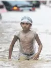  ?? PHOTO: REUTERS ?? Deep water . . . A boy wearing a plastic bag walks along a flooded road in Marikina, Metro Manila, as Typhoon Vamco batters the Philippine capital yesterday.