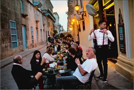  ?? RAMON ESPINOSA/AP PHOTO ?? A waiter serves customers at a private restaurant’s outdoor seating in Havana, Cuba on Wednesday. Eight years after Cuba’s President Raul Castro widened the niche for private enterprise in Cuba’s state-dominated economy, he has thrown the brakes on.