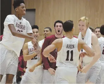  ?? STAFF PHOTO BY CHRIS CHRISTO ?? LATE HEROICS Harvard’s Bryce Aiken celebrates with teammates after hitting the winning 3-pointer in overtime of yesterday’s 70-67 victory against UMass.