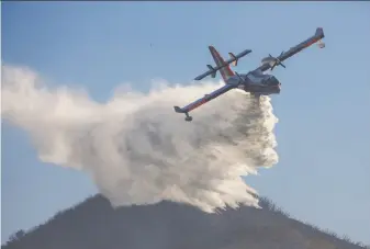  ?? Marcus Yam / Los Angeles Times ?? An aircraft drops water on a hot spot Sunday in the hills near Montecito (Santa Barbara County). More than 8,000 firefighte­rs from nearly a dozen states are battling the huge blaze.