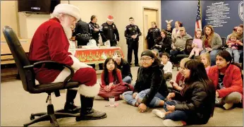  ?? Hunter McFerrin/Siloam Sunday ?? The Siloam Springs Police Department held its annual “Shop with a Cop” event on Thursday night, where a group of kids in the community were able to go on a shopping trip with officers. The event began at the police department, where milk and cookies were served to the kids and their parents, following a visit from Santa. Afterwards, everyone made their way to the Walmart Supercente­r on U.S. Highway 412. Above, a girl waits as Santa begins to answer her question.