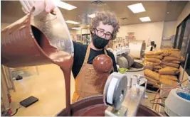  ?? JOHN MCCALL/SOUTH FLORIDA SUN SENTINEL ?? Tyler Levitetz pours artisanal chocolate into a blending machine at his 5150 Chocolate Co. factory Wednesday in Delray Beach.