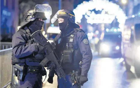  ??  ?? » Oficiales de policía hacen guardia cerca a donde podría ubicarse al atacante tras un tiroteo mortal, en el Mercado de Navidad.