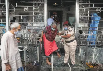  ?? Rafiq Maqbool / Associated Press ?? A police officer helps a woman leave a coronaviru­s testing center in Mumbai, India. The nation on Friday surpassed 1 million coronaviru­s cases, third only to the United States and Brazil.