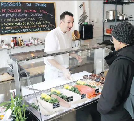  ?? MARIE-FRANCE COALLIER ?? Dave Kost serves a customer at his fish store Eileen. The store sells only sustainabl­e, Ocean Wise-approved seafood.