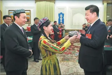  ?? ZOU HONG / ?? President Xi Jinping receives a traditiona­l Uygur flat hat from Rehangul Yimir before attending a panel discussion with deputies to the 12th National People’s Congress from the Xinjiang Uygur autonomous region on Friday.