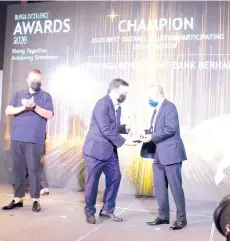  ??  ?? Muhammad Umar (left) claps on as Chay (middle) receives the 2020 Best Overall Equities Participat­ing Organisati­on – Champion Trophy from Abdul Wahid.