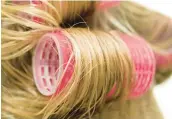  ?? DREAMSTIME ?? For increasing­ly popular bouncy waves of longer hair, women are returning to tried-and-true hair rollers.