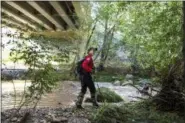  ?? THE ASSOCIATED PRESS ?? A Navajo County rescuer searches the riverbank under the bridge where one body was recovered in Tonto National Forest, Ariz., Monday, July 17, 2017.