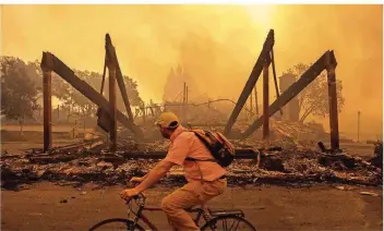  ?? FOTO: PETER THOSHINSKY/DPA ?? Ein Fahrradfah­rer fährt in Santa Rosa, Kalifornie­n, an den Überresten eines Hilton-Hotels vorbei.