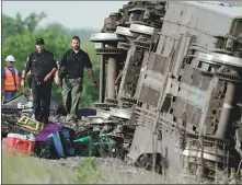  ?? CHARLIE RIEDEL / AP ?? Law enforcemen­t personnel inspect the site where an Amtrak passenger train came off the rails on Monday.