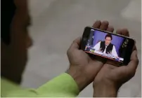  ?? — Reuters ?? A journalist poses with a cell phone displaying Imran Khan, Prime Minister of Pakistan, speaking to the nation in his first televised address.