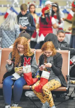  ?? Robin Jerstad / ?? Madison and Katie Maiorana check out their stockings while waiting for the Snowball Express on Saturday at the San Antonio Internatio­nal Airport.