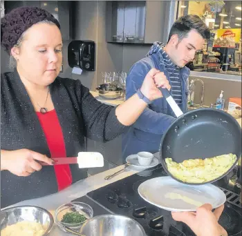  ?? JOSH LEWIS/THE GUARDIAN ?? Jessica Praught scrapes eggs onto a plate alongside fellow Reach Foundation participan­t Liam Mullen during a cooking class at Sobeys Extra in Stratford on Nov. 22.