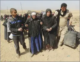  ?? AP PHOtO ?? An Iraqi Army soldier, right, helps displaced civilians as they flee their homes as a result of fighting between Iraqi security forces and Islamic State militants, on the western side of Mosul yesterday.