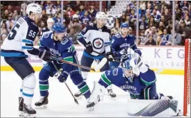  ?? The Canadian Press ?? Vancouver Canucks goalie Jacob Markstrom makes a glove save to stop Winnipeg Jets’ Mark Scheifele as Jets’ Kyle Connor and Vancouver’s Ben Hutton and Troy Stecher look on during the first period Monday in Vancouver. The Jets won 6-3.