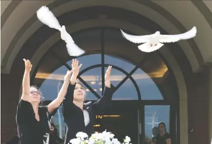  ?? JACQUES BOISSINOT/THE CANADIAN PRESS ?? Josée Masson, left, and Marie-ève Garneau release doves to honour Romy and Norah Carpentier yesterday.