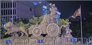  ??  ?? Un operario coloca una bufanda del Real Madrid, anoche, en la estatua de una Cibeles vallada.