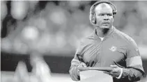 ?? SEAN GARDNER/GETTY ?? Dolphins coach Brian Flores, checking his playbook Thursday during the preseason game against the Saints in New Orleans, is ready to put his total focus on preparing for the Ravens in the season opener.
