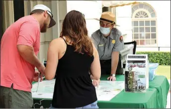  ?? The Sentinel-Record/Tanner Newton ?? REOPENING: Hot Springs National Park Ranger Katy Foster shows two visitors a map of trails from the porch of the Fordyce Bath House on Saturday. Foster said that by noon on Saturday she had counted a few hundred visitors on the porch. On Friday, around 500 people visited the porch.