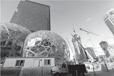  ?? AP Photo/Elaine Thompson ?? Large spheres take shape Oct. 11 in front of an existing Amazon building, behind, as new constructi­on continues across the street in Seattle. For years now, much of downtown Seattle has been a maze of broken streets and caution-taped sidewalks, with...