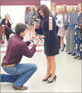  ?? (NWA Democrat-Gazette/Randy Moll) ?? As the Gentry junior high girls championsh­ip basketball team holds letters spelling out, “WILL YOU MARRY ME? Yes? No?” Dakota Place (left) popped the question to Courtney Millsap, the team’s head coach, in March. The proposal came after Millsap presented awards to her team members at a banquet held in the middle school cafeteria. Millsap was blindfolde­d as the letters were distribute­d to teammates. When the blindfold was removed, she saw the proposal, along with Place on bended knee with a ring in his hand. Her answer was “Yes.”