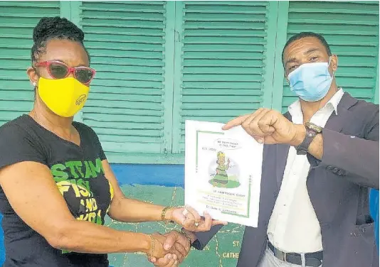  ?? CONTRIBUTE­D ?? Dr Dawn Lemonious (left) presents a copy of her book, ‘Mi Have Sinting Fi Tell Yuh’, to Alanzo Rose, principal at Ulster Spring Primary School in Trelawny.