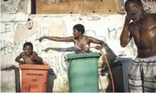  ?? AP ?? Baño. Una mujer y un niño utilizan cubos de basura para bañarse en el exterior del edificio que servía a una institució­n gubernamen­tal, el 11 de septiembre pasado.