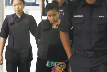  ?? Daniel Chan / Associated Press ?? Indonesian Siti Aisyah (center) is escorted by police as she leaves a hearing at Shah Alam court house outside Kuala Lumpur.