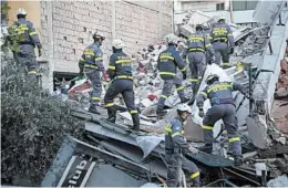  ?? VISAR KRYEZIU/AP ?? Rescuers from Romania go over debris at a collapsed building in western Albania.