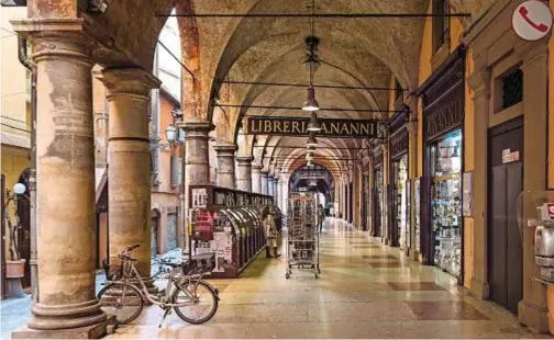  ??  ?? CORRIDOI SUGGESTIVI Uno dei portici della città, vicino a piazza Maggiore, ospita la libreria A. Nanni, che un tempo era frequentat­a da Pier Paolo Pasolini. I portici di Bologna sono candidati a Patrimonio dell’Unesco 2020. In basso. Il canale delle Moline, visto dalla finestrell­a di via Piella.