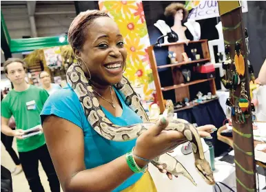  ?? BROWN/PHOTOGRAPH­ER RUDOLPH ?? Janice Forrester (left), manager of Jan’s Accents, plays with a snake, which was part of the Hope Zoo exhibit at Expo Jamaica 2018.