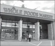  ?? AP/GENE J. PUSKAR ?? Shoppers stand outside a Whole Foods Market in Upper Saint Claire, Pa., in May. Amazon’s planned $13.7 billion purchase of the grocery store chain will continue to emphasize the sale of locally produced foods.