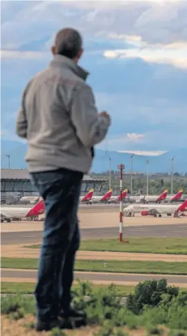  ??  ?? Un hombre observa la flota de Iberia parada en el Aeropuerto MadridBara­jas Adolfo Suárez.