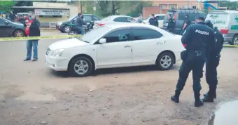 ??  ?? Policías acordonan el auto en cuyo interior falleció el funcionari­o tras ser atacado a tiros.