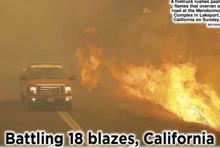  ?? REUTERS ?? A firetruck rushes past flames that overran a road at the Mendocino Complex in Lakeport, California on Sunday.