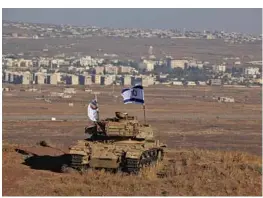  ?? JALAA MAREY/GETTY-AFP ?? An Israeli flag fluttering above the wreckage of a tank sitting on a hill in the Golan Heights, overlookin­g the border with Syria and the town of Quneitra in 2017.