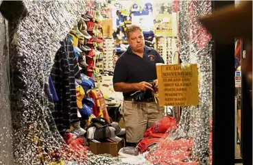  ?? — Reuters/AP ?? Shattered peace: A man preparing to remove glass shards from a broken shop window after (bottom) protesters become unruly in St Louis.