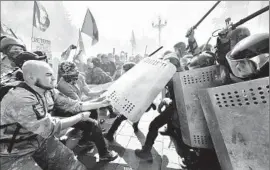  ?? Sergei Supinsky AFP/Getty Images ?? IN KIEV, activists of right-wing Ukrainian parties clash with police near the parliament. A national guardsman was killed and more than 120 people were hurt.