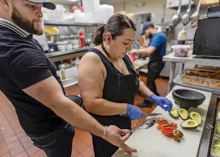  ?? JIM WEBER/THE NEW MEXICAN ?? Elder Guzmán, owner of the Dos Amigos Sports Mexican Restaurant, visits his mom, Veronica Guzmán, in the kitchen before the evening rush Friday. “She’s the heart of the place,” Elder Guzmán said. “She for sure keeps everybody together when there’s conflict.”