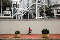  ??  ?? HONG KONG: A woman walks past a gas refinery in the To Kwa Wan district of Hong Kong on Friday. —AFP