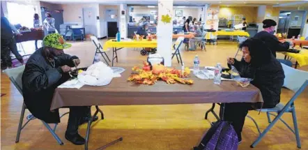  ?? NELVIN C. CEPEDA U-T ?? Marcelino Lopez and Alicia Mercano enjoy their hot Thanksgivi­ng dinner Saturday at the San Diego Rescue Mission. Because of the pandemic, with the exception of limited tables inside, the majority of dining tables had to be set up in the parking lot.