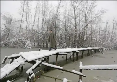  ??  ?? A man walks on a footbridge during a snowfall in Srinagar, on Friday. REUTERS