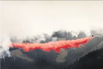  ?? Kurt Wilson / Missoulian ?? A tanker drops fire retardant Friday below the blaze burning southwest of Lolo in western Montana. The 44-square-mile blaze has forced the evacuation of hundreds of homes.