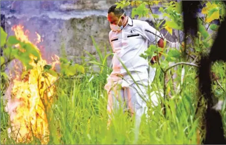  ?? AFP ?? A gravedigge­r burns his protective gear after lowering the coffin of a Covid-19 victim at a cemetery in Banda Aceh, Indonesia.