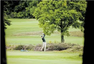  ?? MATT DUNHAM THE ASSOCIATED PRESS ?? A golfer hits a shot on Wednesday after the reopening of a golf club in Sunningdal­e, England.