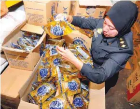  ??  ?? ... Malacca Domestic Trade, Cooperativ­es and Consumeris­m Ministry assistant enforcemen­t officer Zulia Mat Yusof checking the price tags of the 1kg polybag cooking oil at a grocery store in Merlimau, Jasin. The price remains unchanged, at RM2.50, after...