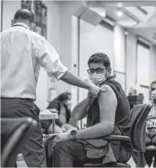  ?? REUTERS ?? The team lead from Humber River Hospital’s mobile vaccine clinic, Ruben Rodriguez, administer­s the first dose of the Moderna vaccine to an employee of pharmaceut­ical company Apotex in Toronto on April 13.